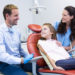 Dentist interacting with mother and daughter while dental examination